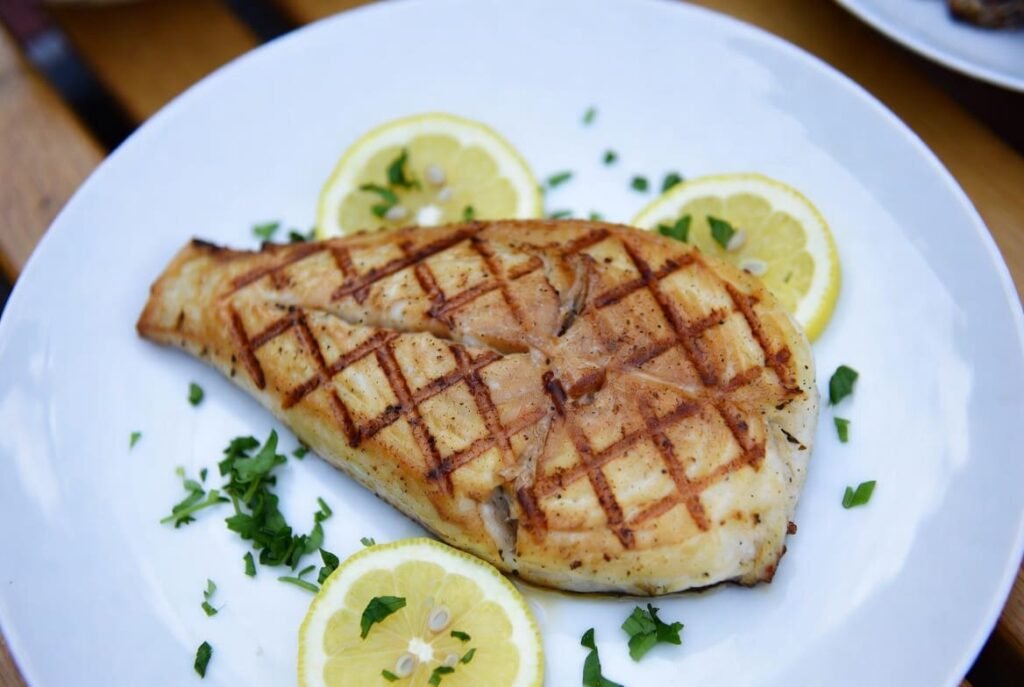 Grilled common carp fillet served with lemon and herbs